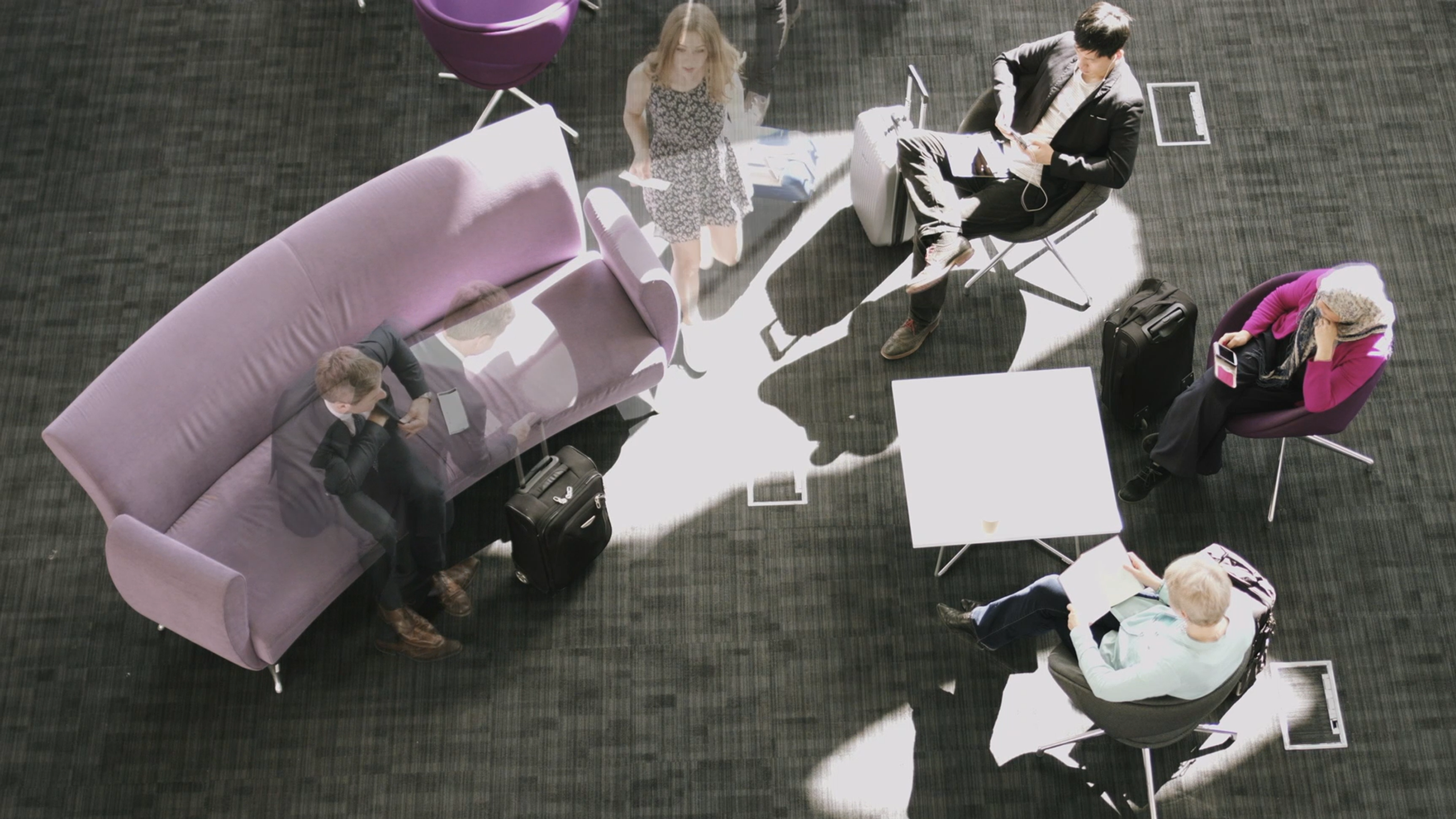 An overhead image of business people at work. A few of them are dissolving out of view.