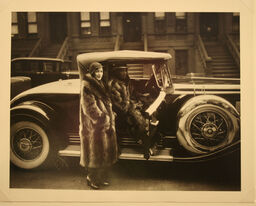Two people standing in front of a car