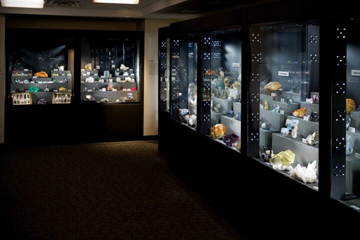 Darkened gallery with lighted cases showing colorful minerals.