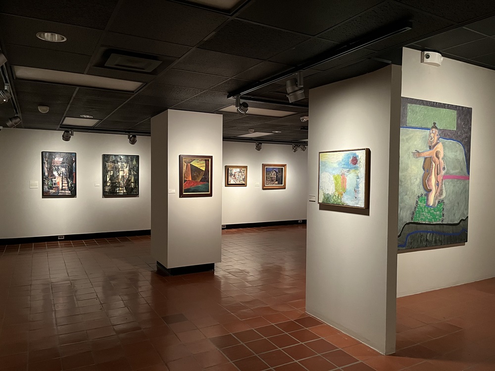 Art gallery with paintings on walls, many wall segments and a square column with paintings on it.