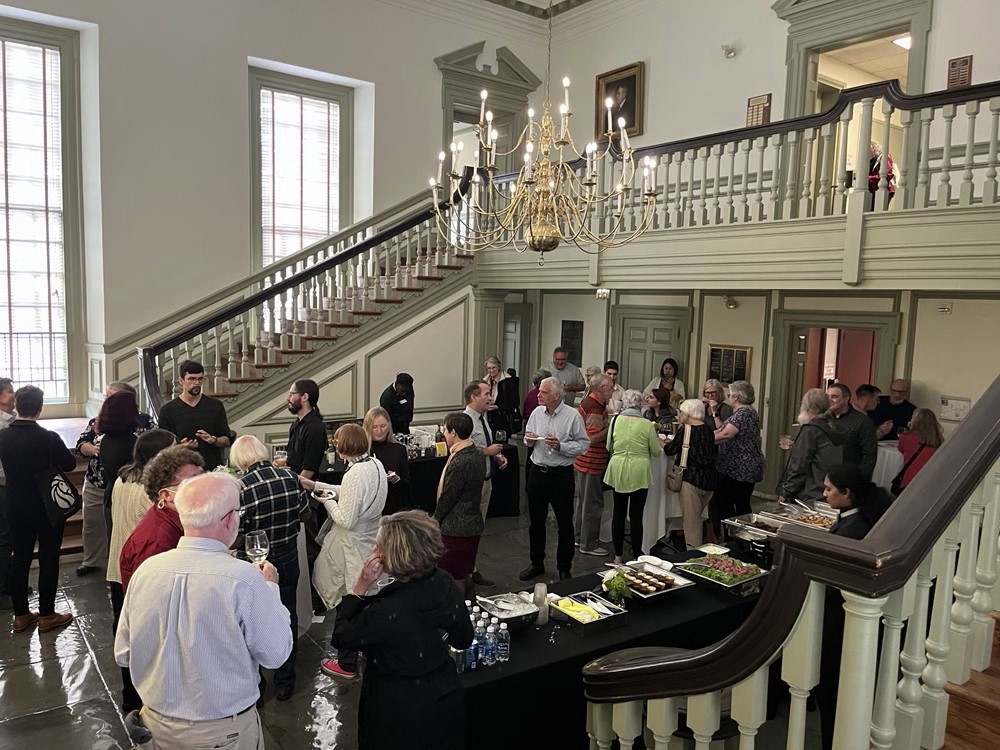 Large group of people mingling at a reception in the lobby of a formal staircase