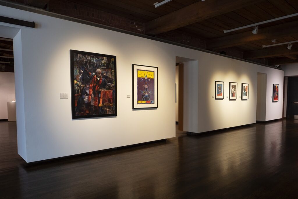 Art gallery with wood floors and white walls, art on walls.