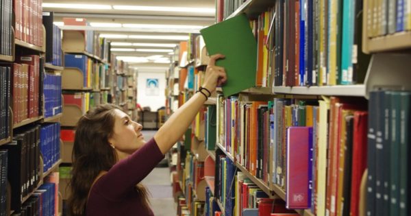 Student pulling a book off the shelves