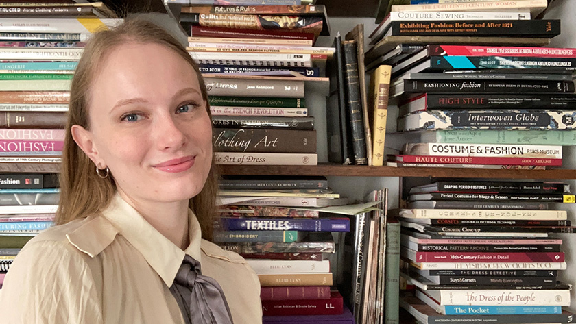 A young women off to the left standing in front of two shelves packed with books