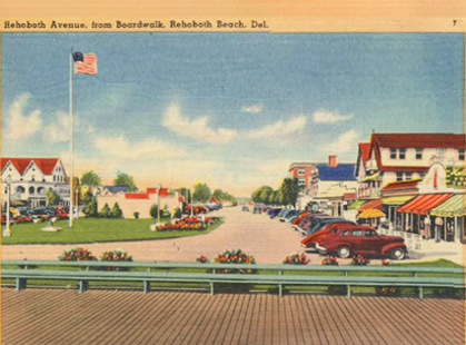 A color postcard showing paved roads, cars and the edge of the boardwalk in Rehoboth