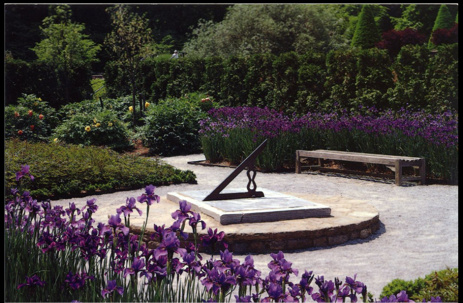 A postcard of a sundial surrounded by walking paths and flowers
