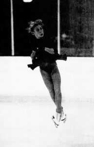 A young woman mid-routine at a figure skating competition.