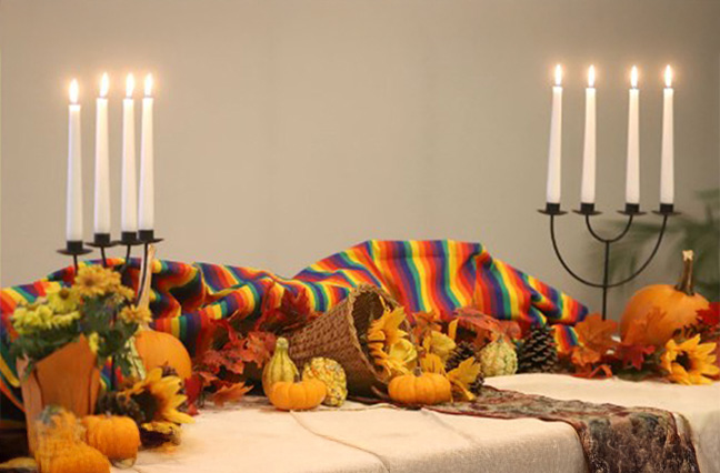 A table is set with cornucopias and candles for a Thanksgiving feast.