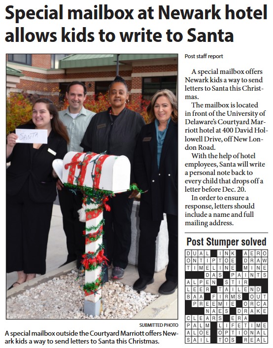 Postal workers pose with a holiday-theme decorated Santa's Mailbox.
