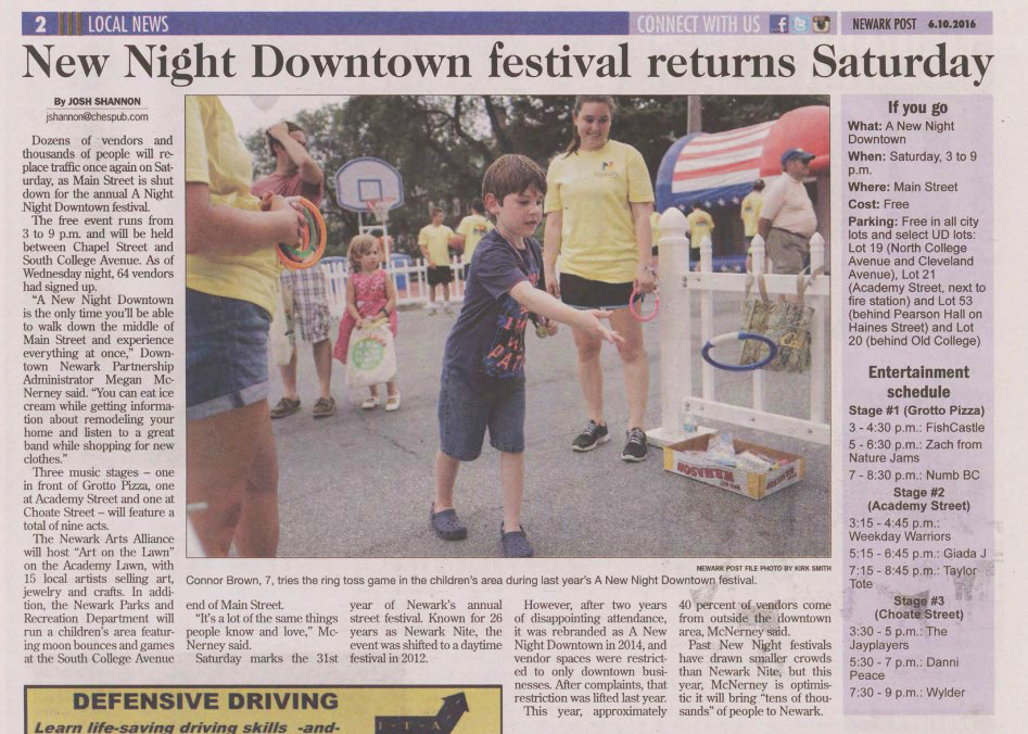 A newspaper clipping from the Newark Post features a photograph of a young boy throwing a ring at a ring toss game during a festival. The surrounding article text details the upcoming "A New Night Downtown" festival, including parking information and an entertainment schedule for three different stages.