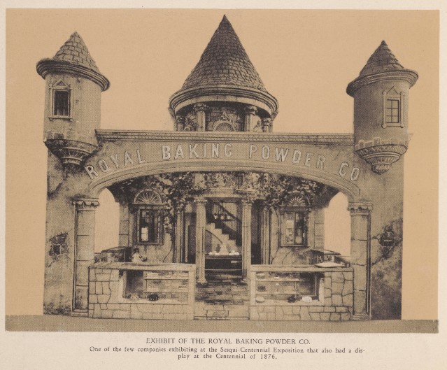 A sepia photograph displaying the exhibition booth for the Royal Baking Powder Co. The structure mimics a medieval stone castle facade complete with turrets, a central conical roof, and vines trailing down the walls.