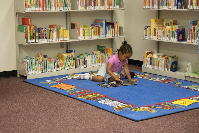 The child of a student-parent enjoys a book in the corner of Morris Library’s newly opened Family Study Space.