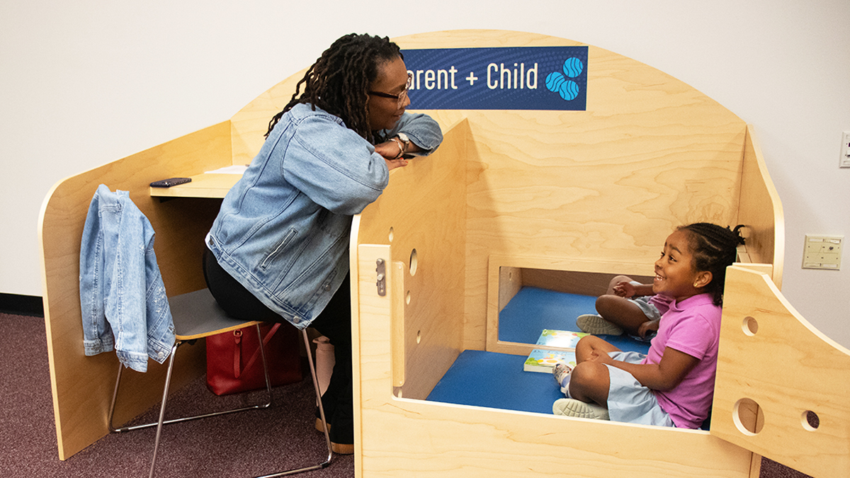 Adult and child sharing a warm reading moment inside a small wooden