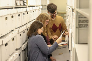 Three Special Collections staff members reviewing a box of archival materials
