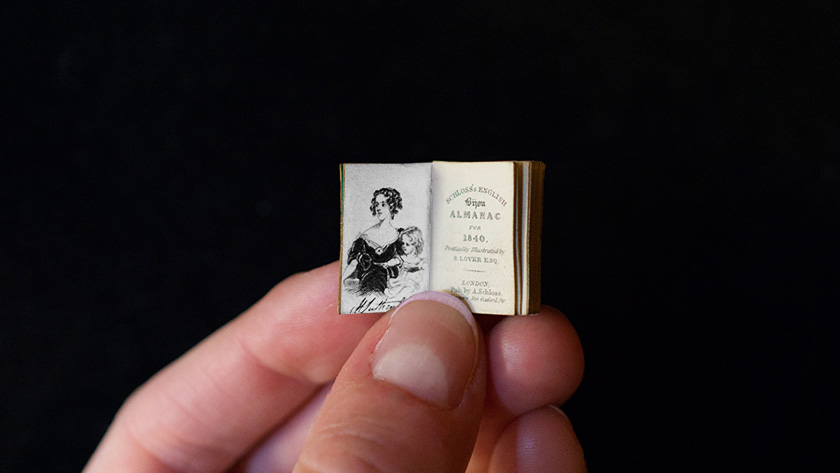 A close-up of fingers holding an especially tiny book.