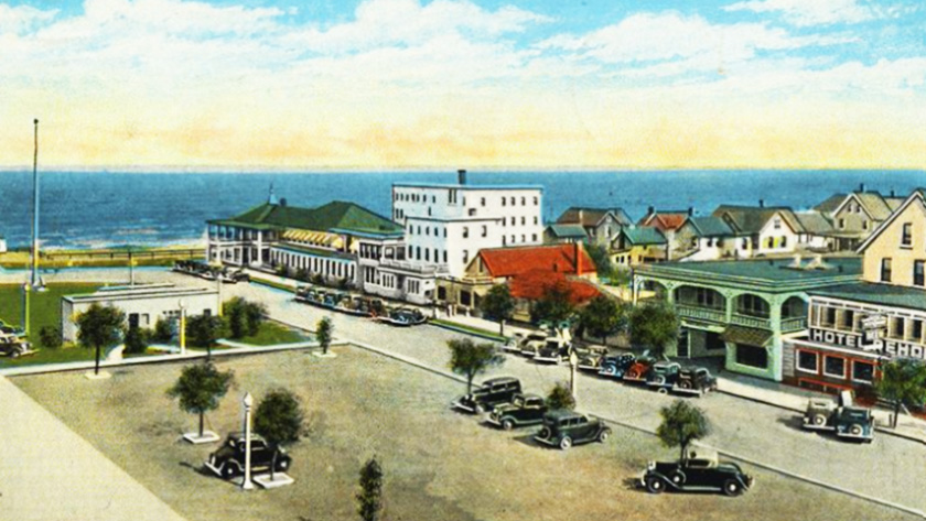 A color postcard showing paved roads and parked cars on Rehoboth Avenue