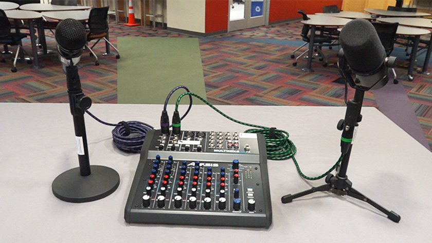 Two microphones plugged into an audio mixer, sitting on a table.